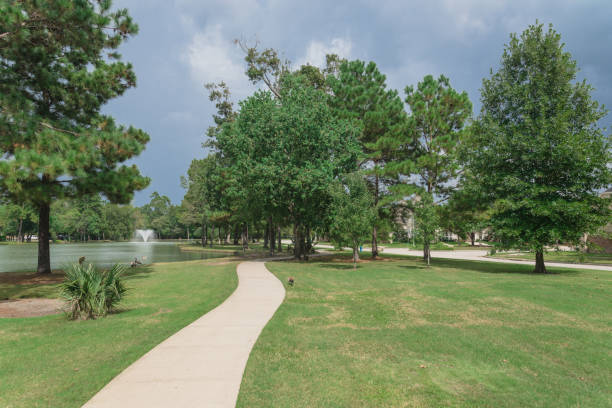 istock Empty concrete pathway thru neighborhood park with water fountain and ducks swimming in Houston, Texas, USA 1285642638