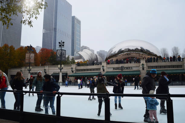 People ice-skating in front of Chicago landmark and tourist attraction People ice-skating in downtown Chicago on a cloudy winter day with skyscrapers and the famous tourist attraction Cloud Gate (Chicago bean) in the background millennium park chicago stock pictures, royalty-free photos & images