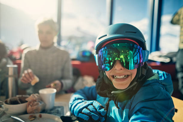 Family skiing in the Alps. Little boy waiting for lunch in ski restaurant.\nShot with Nikon D850.