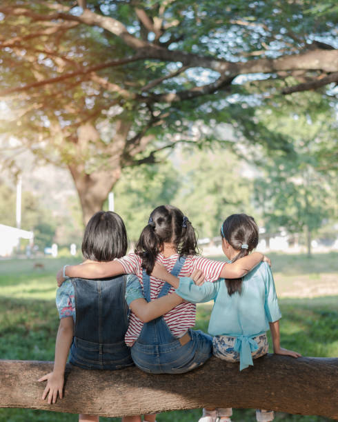 kinder freundschaft konzept mit glücklichen mädchen kinder im park spaßig sitzen unter baum schatten spielen zusammen genießen gute erinnerung und moment der studenten lebensstil mit freunden in der schule - 5 month old stock-fotos und bilder