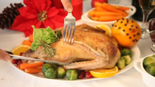 Table served for thanksgiving or Christmas dinner. Woman hand cutting stuffed roasted turkey. Traditional celebrating holiday