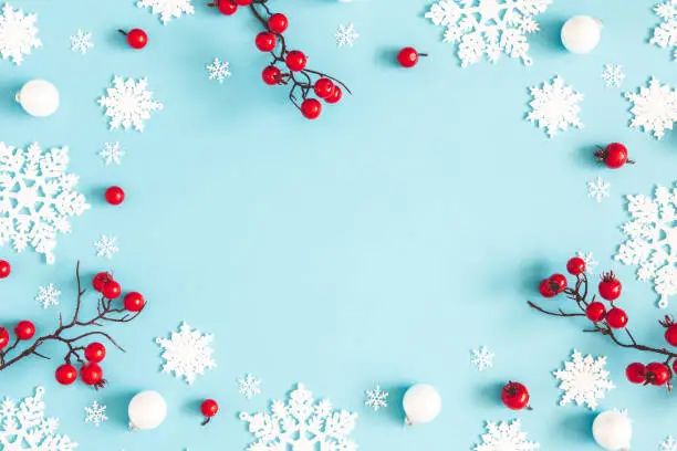 Photo of Christmas or winter composition. Snowflakes and red berries on blue background. Christmas, winter, new year concept. Flat lay, top view, copy space