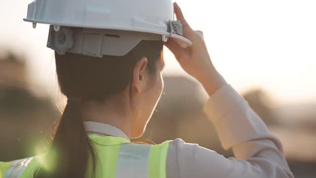 Occupation,Engineer,Hardhat,Safety, Slow motion close up of a woman engineer putting a construction helmet on at sunset Career, success, work and engineering Concept.
Shoot format on 4K 4:2:2 10bit All-i