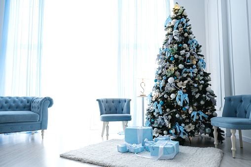 Beautiful Christmas tree with blue decor in a white room.