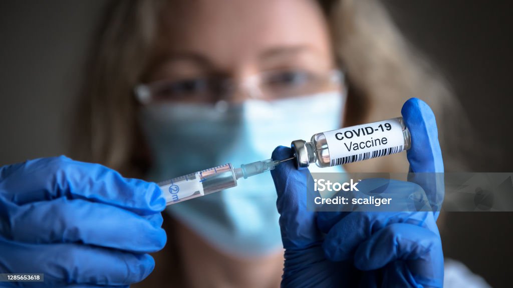 COVID-19 coronavirus vaccine in doctor hands COVID-19 vaccine in researcher hands, female doctor holds syringe and bottle with vaccine for coronavirus cure. Concept of corona virus treatment, injection, shot and clinical trial during pandemic. COVID-19 Vaccine Stock Photo