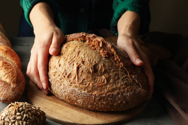 istock Woman hold fresh baked bread on gray table 1285654904