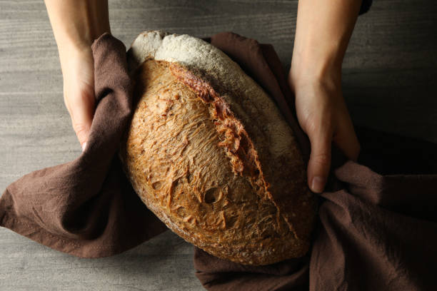 istock Female hands with napkin hold fresh bread on gray background 1285655314