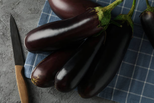 istock Napkin with fresh eggplants and knife on gray background 1285657421