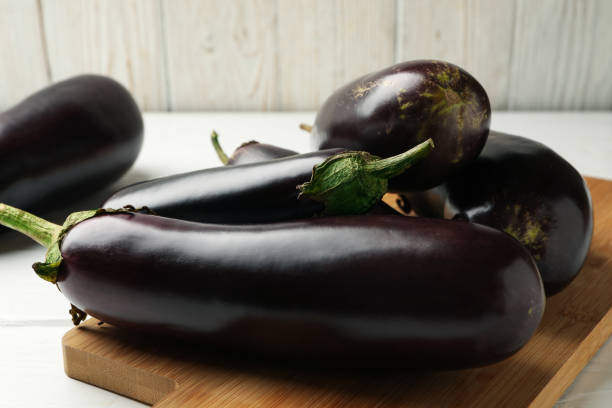 istock Board with fresh eggplants on wooden background 1285657562