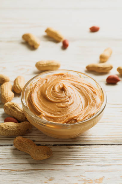 istock Peanut and bowl with peanut butter on wooden background 1285658669