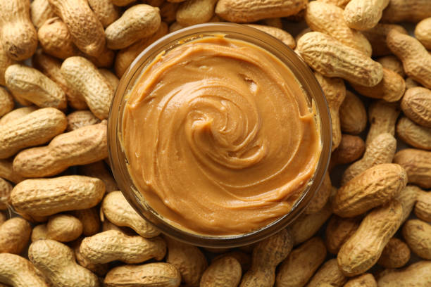 istock Jar with peanut butter on peanut background, close up 1285658884