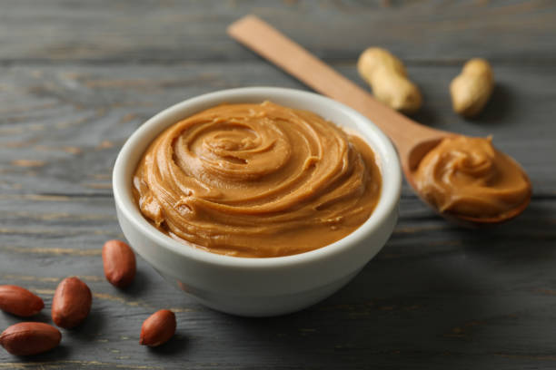 istock Bowl and spoon with peanut butter on wooden background 1285658947