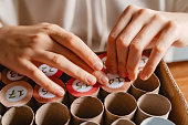 Girl making handmade advent calendar house from toilet paper rolls and carton box, close up. Sustainable Christmas, upcycling, zero waste, affordable gift.