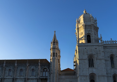 Lisbon, Portugal, March 16, 2019: The sun's rays rest on the Jeronimos Monastery in Belem district. The monastery is one of the most prominent examples of the Portuguese Late Gothic Manueline style of architecture in Lisbon. It is listed as a UNESCO World Heritage Site.