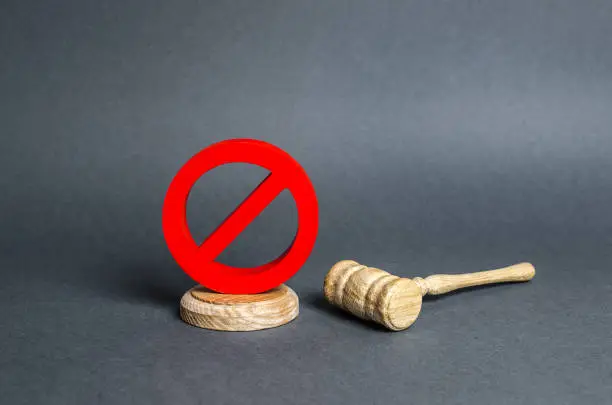 Photo of The red prohibitory symbol no stands on the stand and prevents the hammer from making a verdict. Anti popular laws, usurpation of power. Lack of justice. Veto. Challenging a court decision.