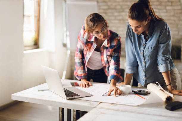 istock Young creative businesswomen  working on blueprints in the office 1285670481