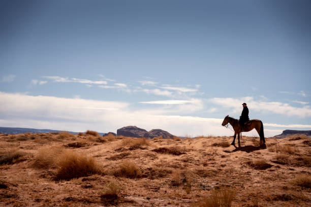 Mature Hispanic Man rides his horse through the rugged Desert in Northern Arizona near the Monuement Valley Tribal Park in Indian Country Mature Hispanic Man rides his horse through the rugged Desert in Northern Arizona near the Monuement Valley Tribal Park in Indian Country monument valley photos stock pictures, royalty-free photos & images