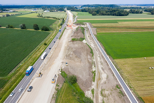 Construction of a highway, aerial view, truck and cars driving on the road.