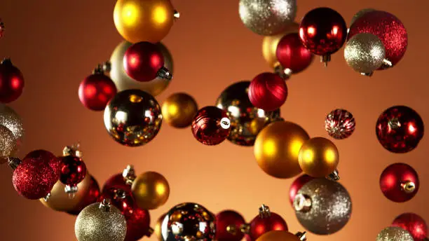 Flying christmas balls on coloured background, concept of celebrating, studio shot.