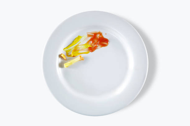 Looking down on an eaten meal with mustard, ketchup  and french fries