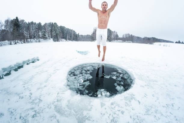 junger mann bereitet sich auf das schwimmen im eisloch vor - winter lake snow water stock-fotos und bilder