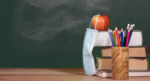 istock Back to virtual school background concept with stack of books and apple with face mask 1285678488