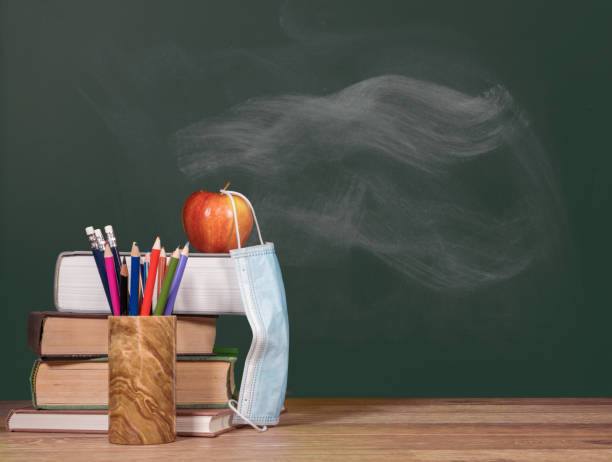 istock Back to virtual school background concept with stack of books and apple with face mask 1285678517