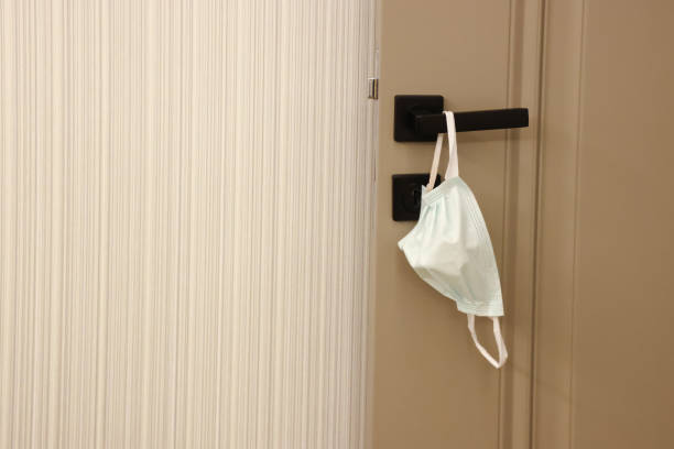 istock Close-up of Protective Face Mask Hanging on Front Door Handle 1285680859