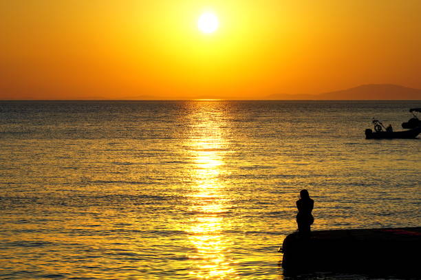 Beautiful summer sunset with silhouette of loneliness girl on a dock