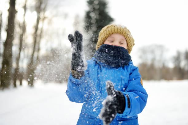 新雪で遊んで楽しんでいる小さな男の子。雪合戦。雪の多い冬の日に子供のためのアクティブな屋外レジャー。 - 11321 ストックフォトと画像