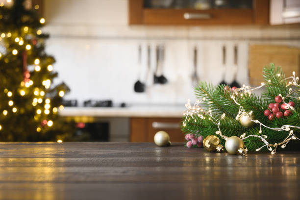 Wooden tabletop with gold gift Christmas decoration and blurred modern kitchen as background.