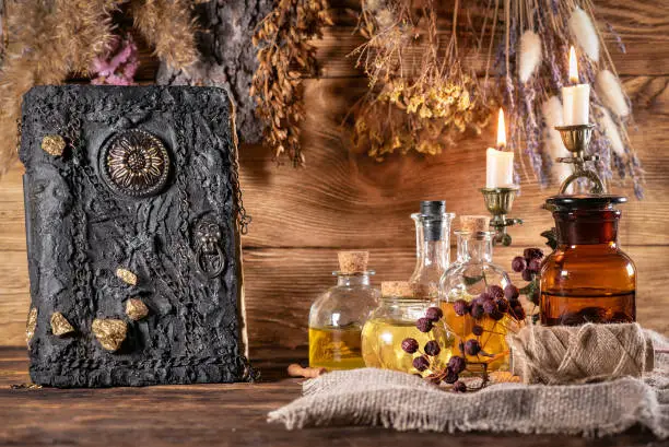 Spell book, magic potion and dried herbs on the witch table concept.