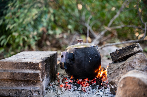 Water is boiled to make tea over wood fire. the kettle is black with smoke.