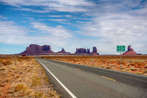 Driving On Scenic Highway 163, The Navajo Code Talker Highway That Runs Through Monument Valley, Arizona, With The Famous Beautiful Monuments In The Background