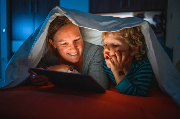 istock Cute blond boy and his mother using digital tablet at bedtime 1285686820