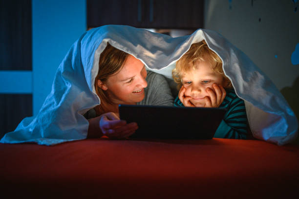 istock Cute blond boy and his mother using digital tablet at bedtime 1285686821