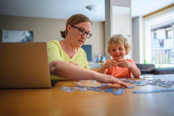 istock Mother working at home and helping son collecting puzzles at the same time 1285687903