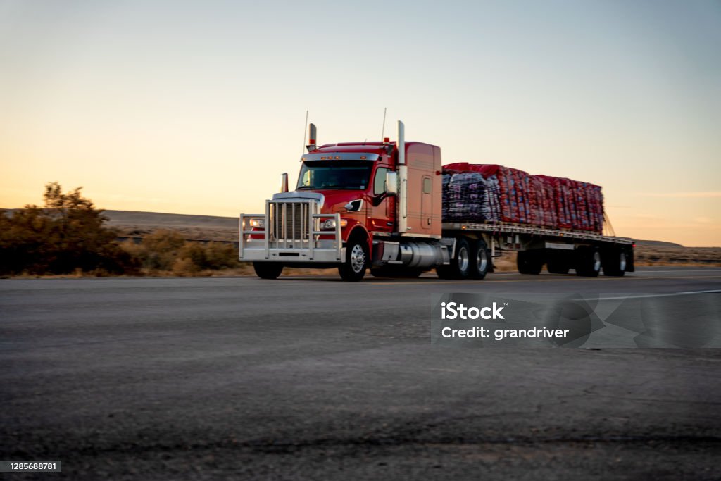 A Semi Truck Passing By On A Lonely Two-Lane Highway In Utah, Hauling A Load In The Trailer To The Final Destination Semi-Truck Stock Photo