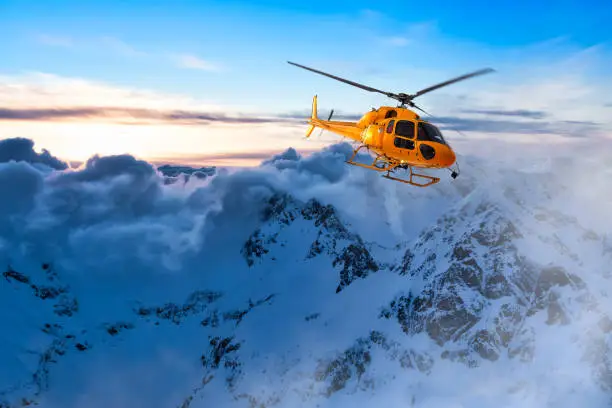 Yellow Helicopter flying over the Rocky Mountains during a colorful sunset. Aerial Landscape from British Columbia, Canada near Vancouver. Epic Adventure Composite