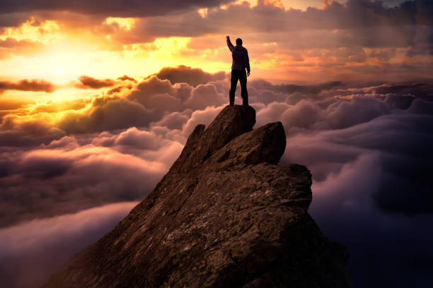 istock Fantasy Adventure Composite with a Man on top of a Mountain Cliff 1285691188