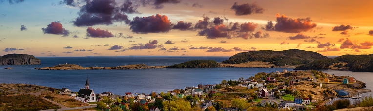 Aerial panoramic view of a small town on the Atlantic Ocean Coast. Dramatic Colorful Twilight Sky. Sunset or Sunrise. Taken in Trinity, Newfoundland and Labrador, Canada.