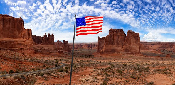 American National Flag. Panoramic landscape view of a Scenic road in the red rock canyons. Blue Sky and White Clouds. Taken in Arches National Park, located near Moab, Utah, United States.