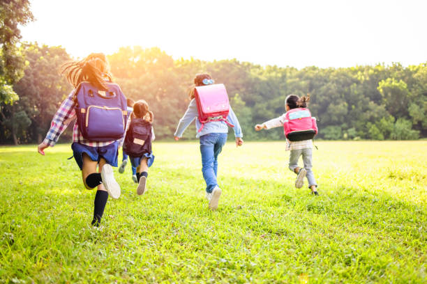 istock rear view of elementary school kids running on the grass 1285694120