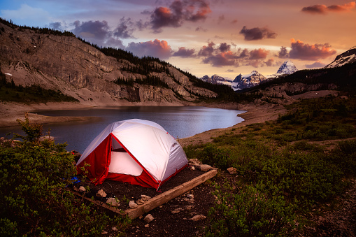 Camping Tent in the Iconic Mt Assiniboine Provincial Park near Banff, Alberta, Canada. Canadian Mountain Landscape in Background. Sunset Sky. Concept: Adventure, Hiking, Backpacking, Freedom