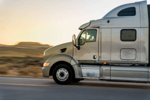 ein sattelschlepper fährt auf einem einsamen zweispurigen highway in utah vorbei und fährt eine ladung im anhänger zum ziel - empty nobody two lane highway highway stock-fotos und bilder