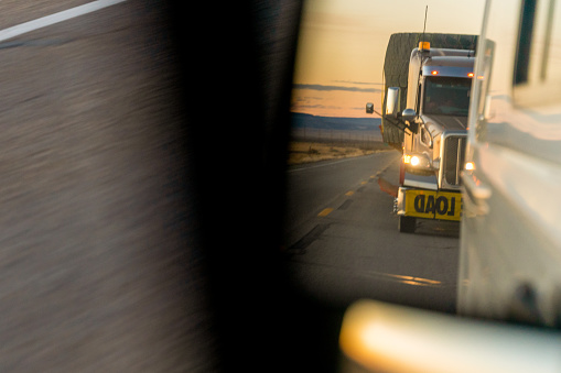 A Closeup View Of A Long Haul Semi Truck In The Rearview Mirror Following Too Close Behind