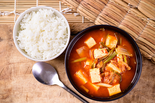 Korean food, Kimchi soup with fofu eating with cooked rice on wooden background, Top view