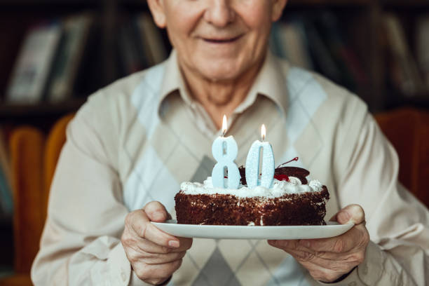 istock Senior man alone sitting at library holding cake close-up smiling 1285702985
