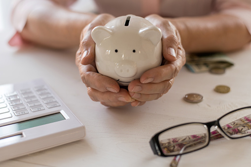 Old women's hands put money in the piggy Bank, the concept of retirement, savings.