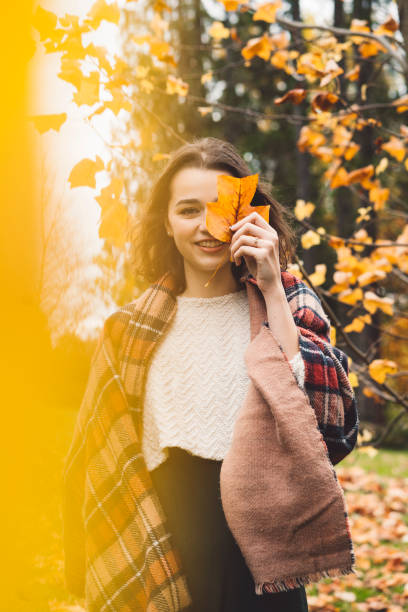 istock Smiling woman covering her fece with a yellow leaf 1285703660